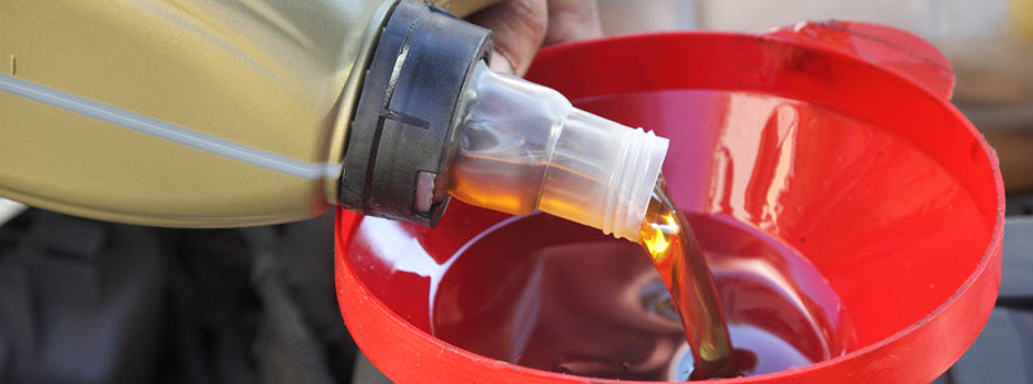 Oil being poured into engine with red funnel